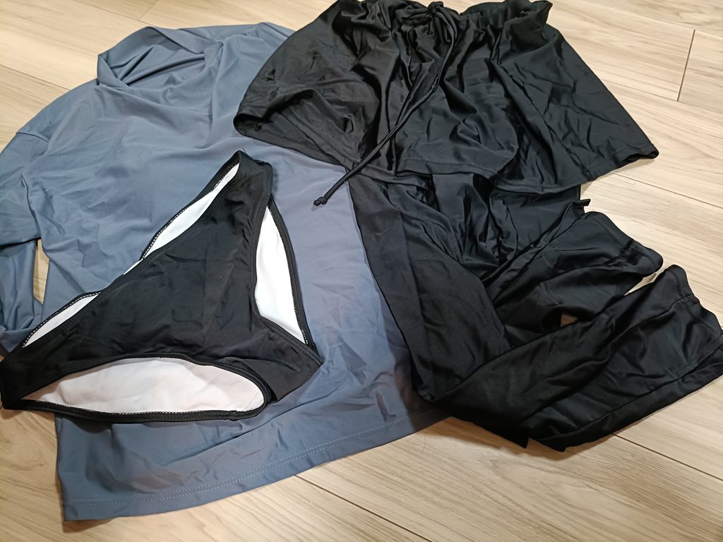 床に並べた筆者のラッシュガードと黒い水着類